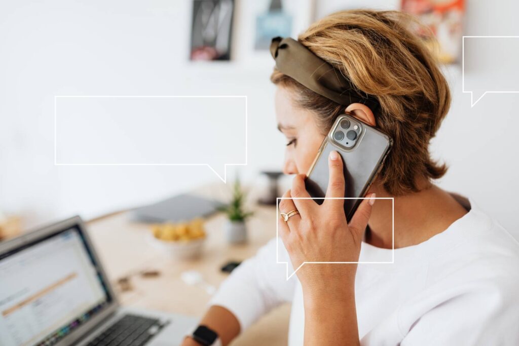 Kobieta pracująca przy laptopie, trzyma przy uchu telefon i prowadzi rozmowę.