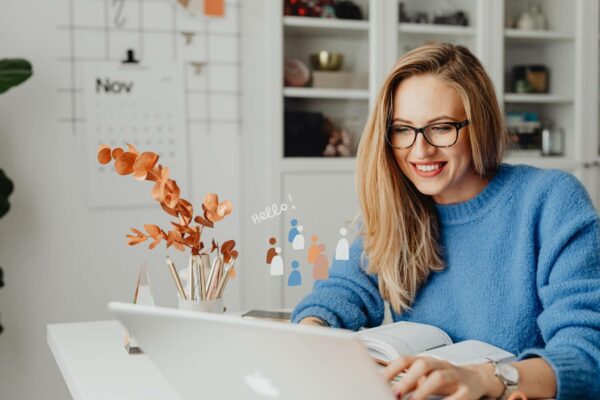 Uśmiechnięta, młoda kobieta pracująca przy laptopie