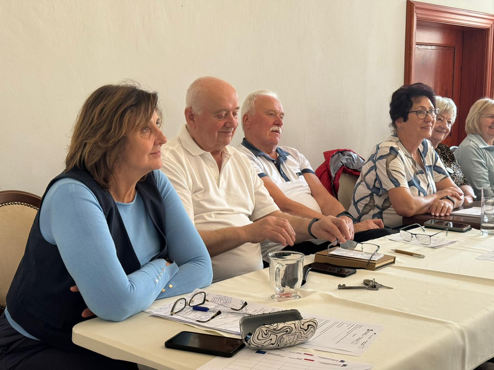 grupa uczestników szkolenia siedzi przy stołach i pozuje do zdjęcia