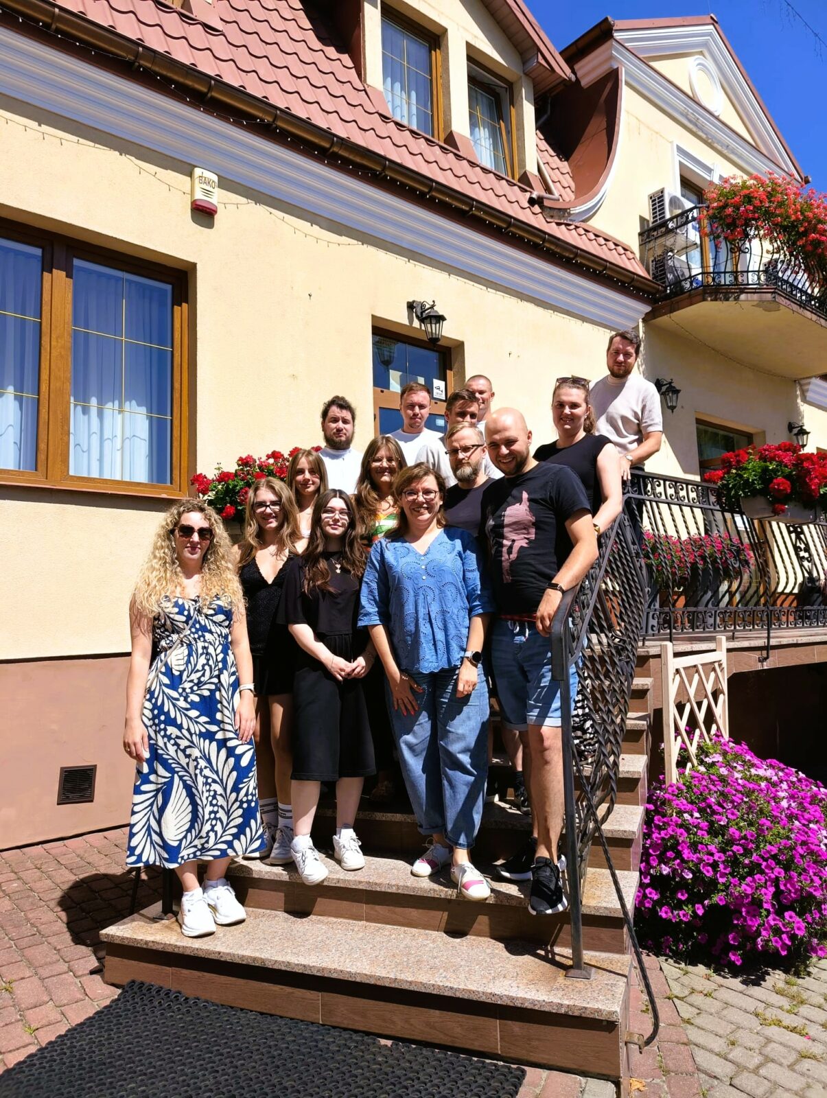 zdjecie grupowe uczestników szkolenia - grupa osób stoi przed hotelem i pozuje do zdjęcia