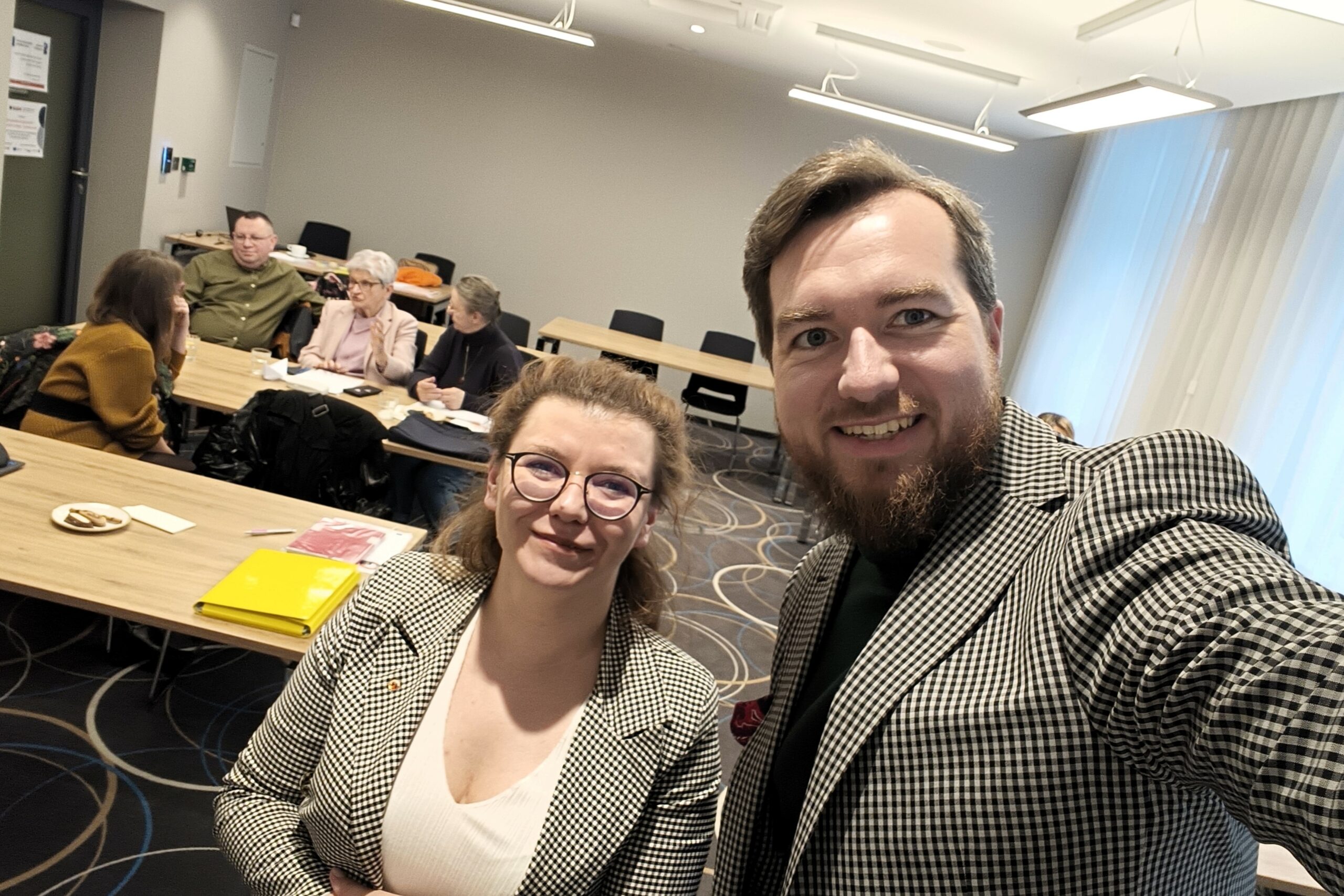 dwie osoby pozują do selfie na sali szkoleniowej